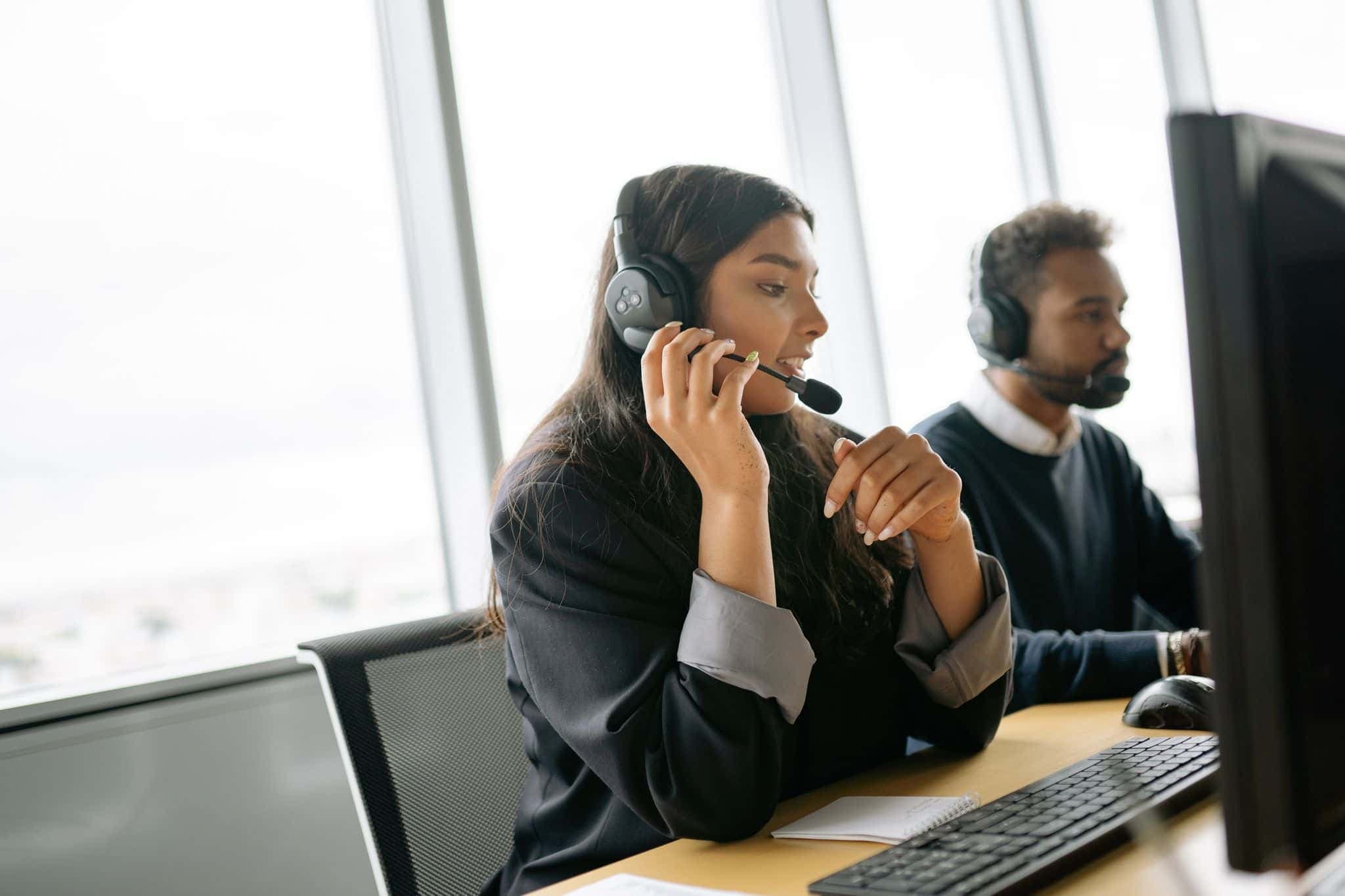 Customer service agents with headsets working at computers in an office.