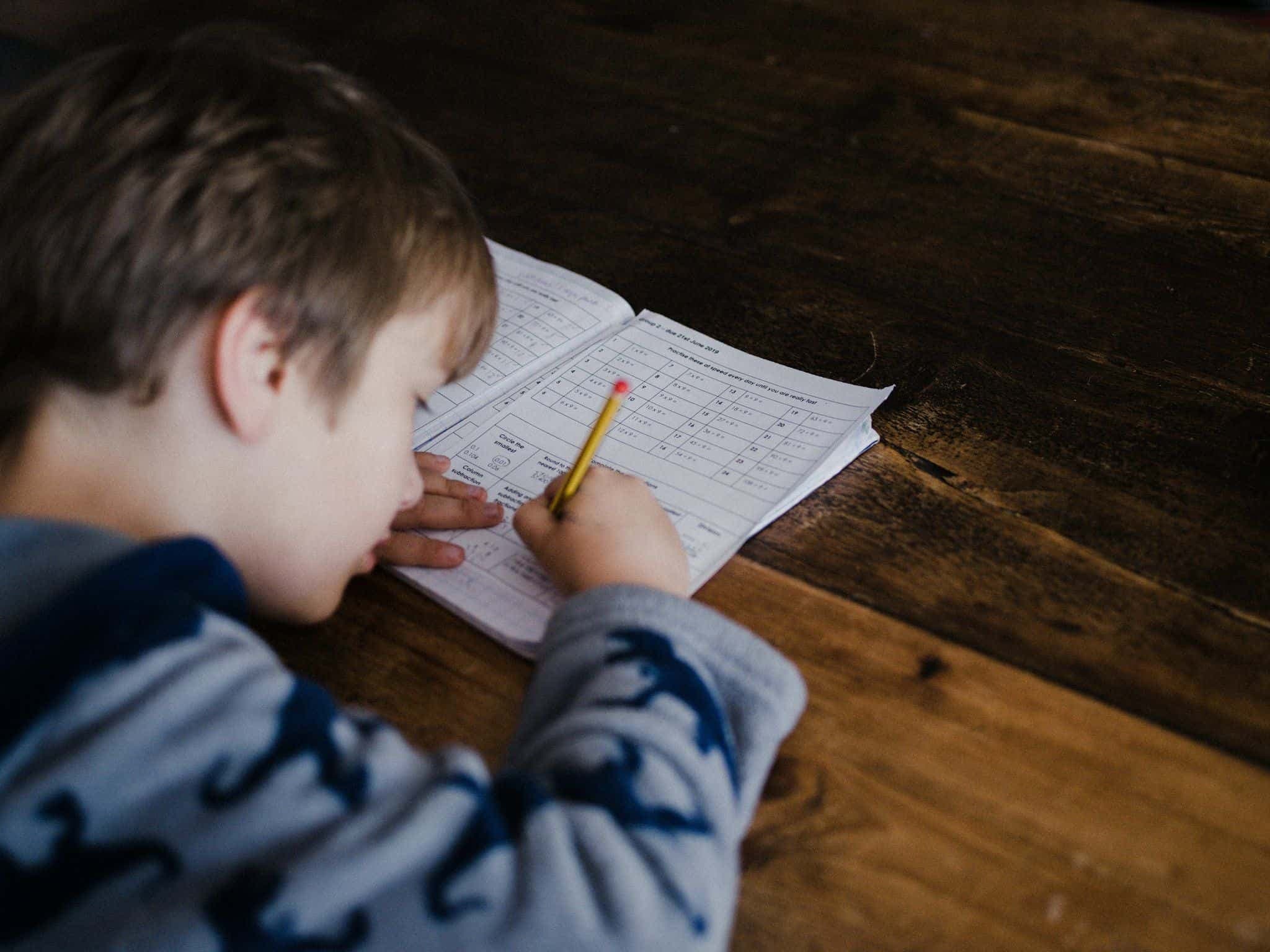 A boy writing in a workbook at a table.