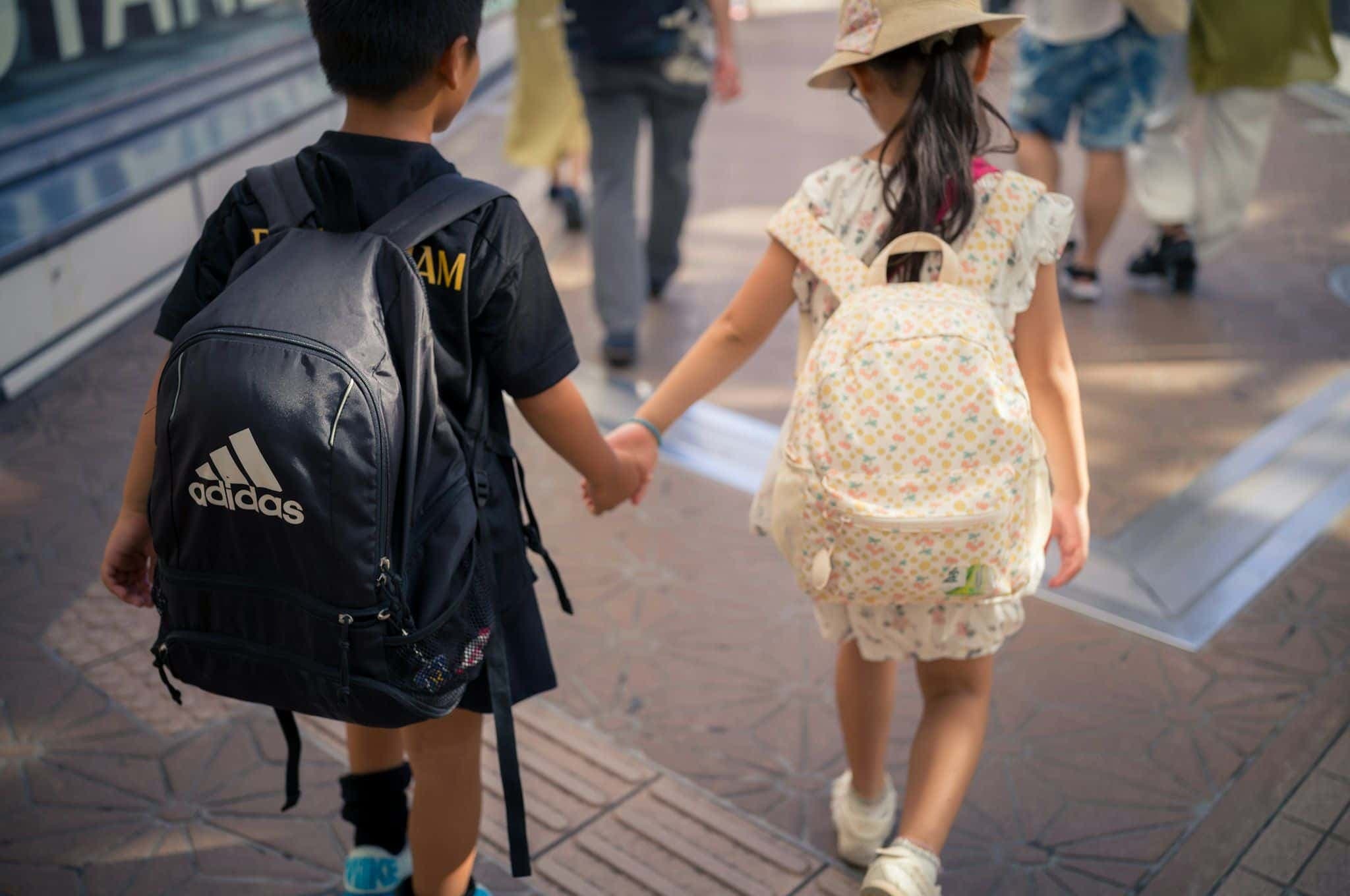 Two children walking down a street holding hands.
