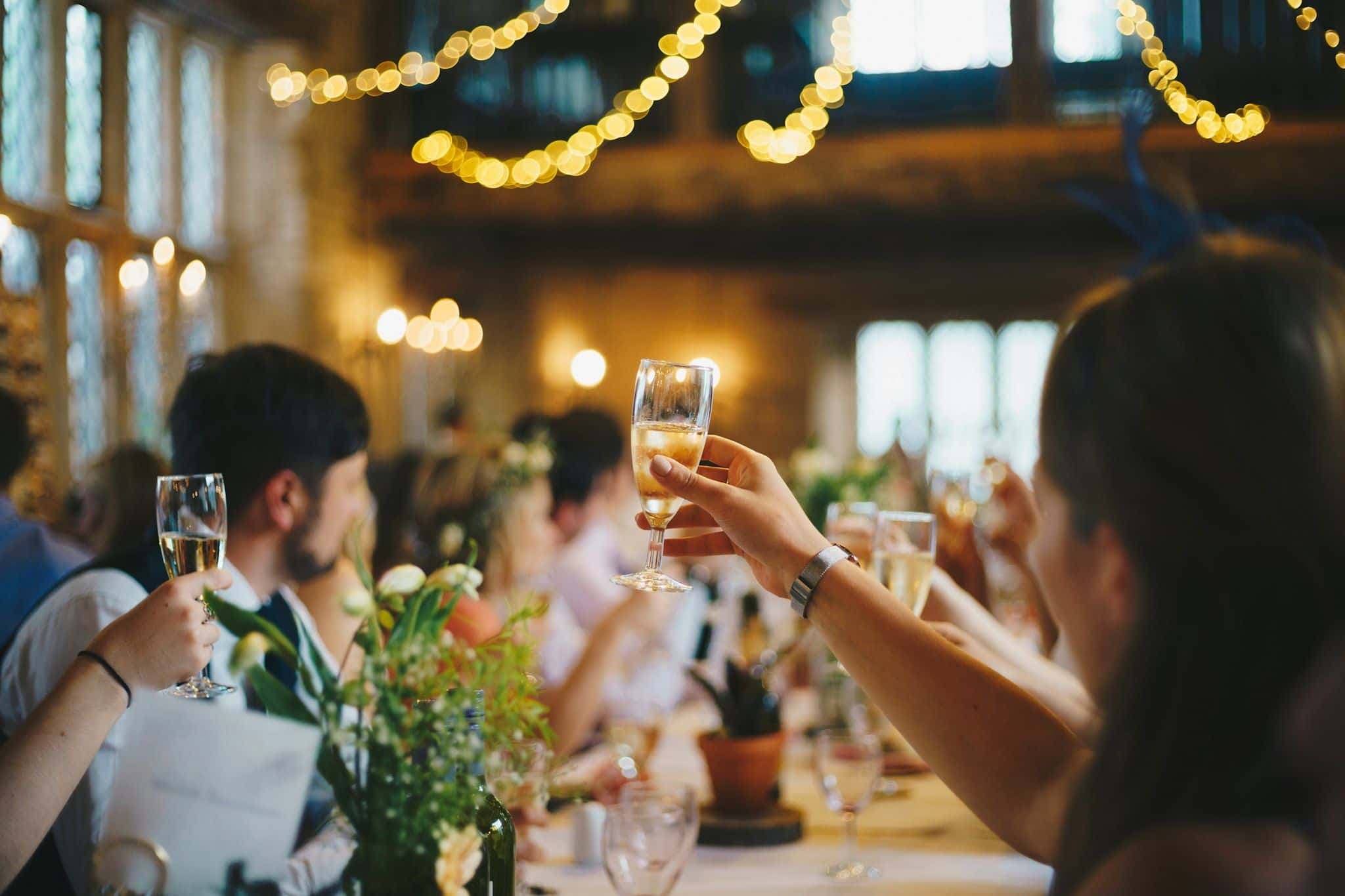 Wedding guests raising glasses together in a toast.