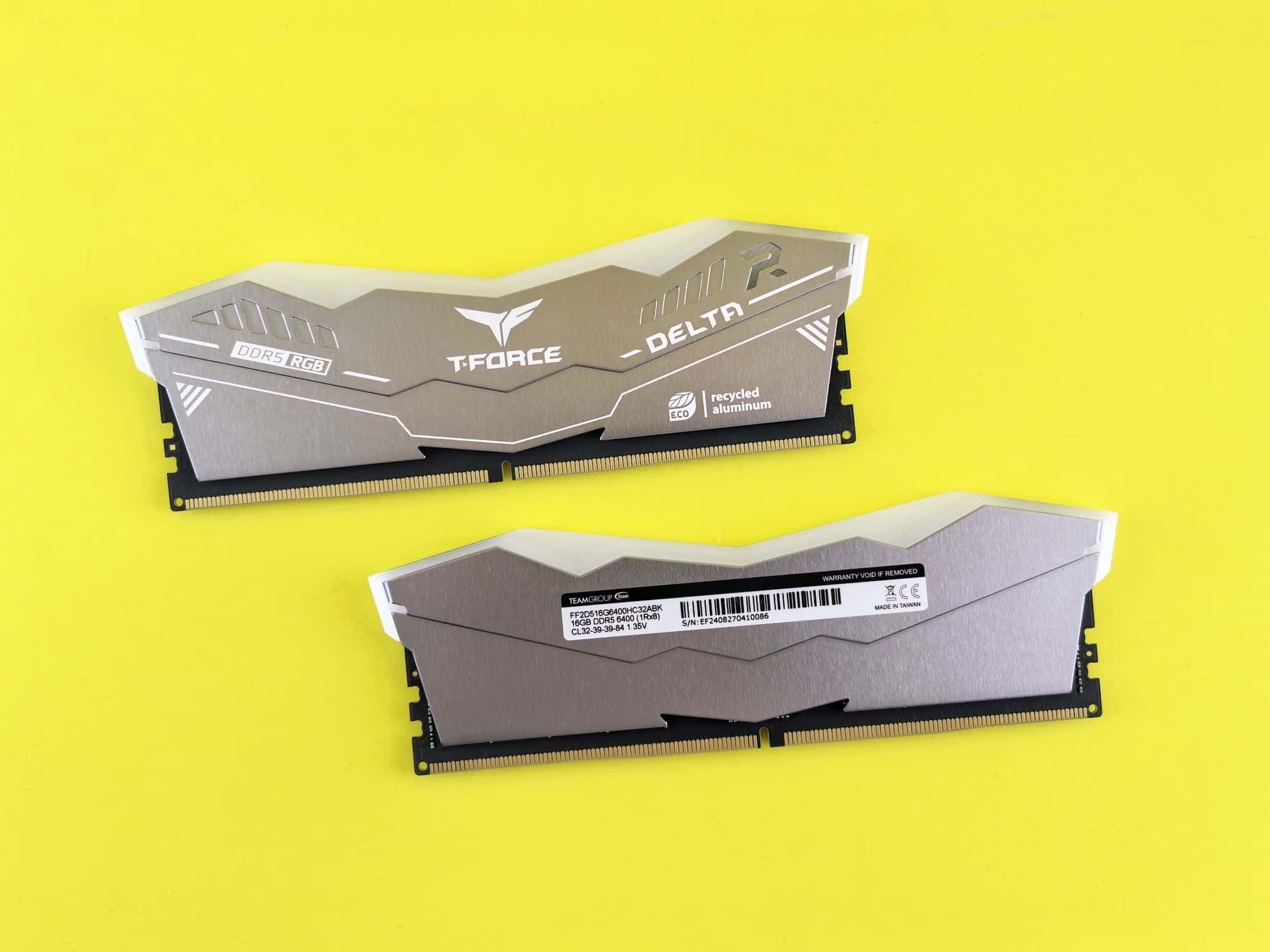 Two DDR5 memory modules lying on a bright yellow surface.