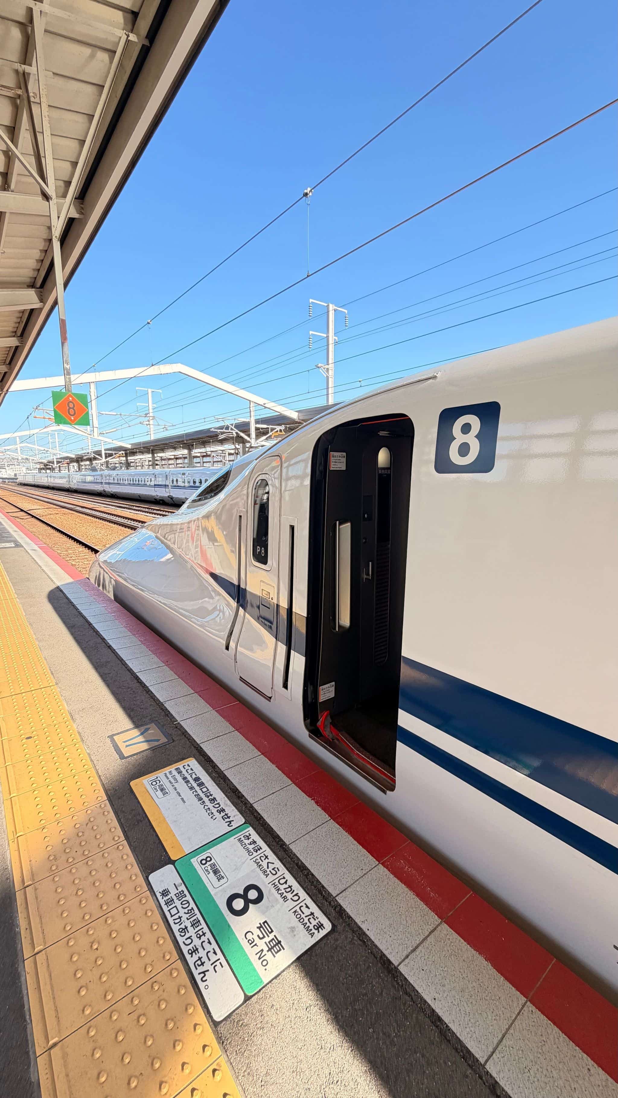 A shinkansen bullet train waiting at a platform at Kyoto Station.