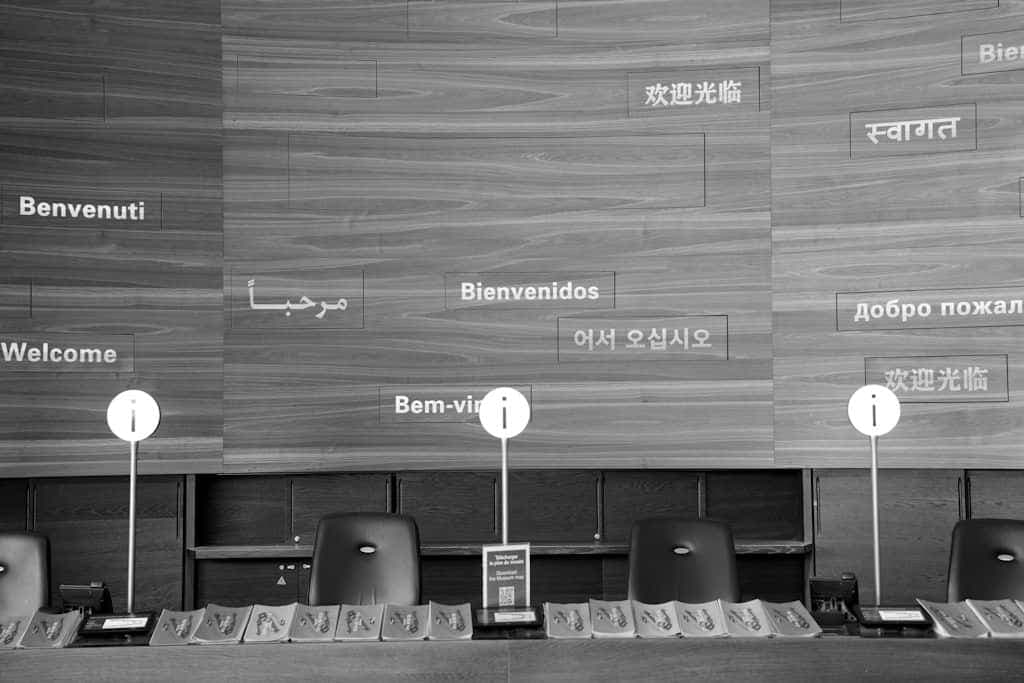 A wooden wall with the word welcome written in many different languages.