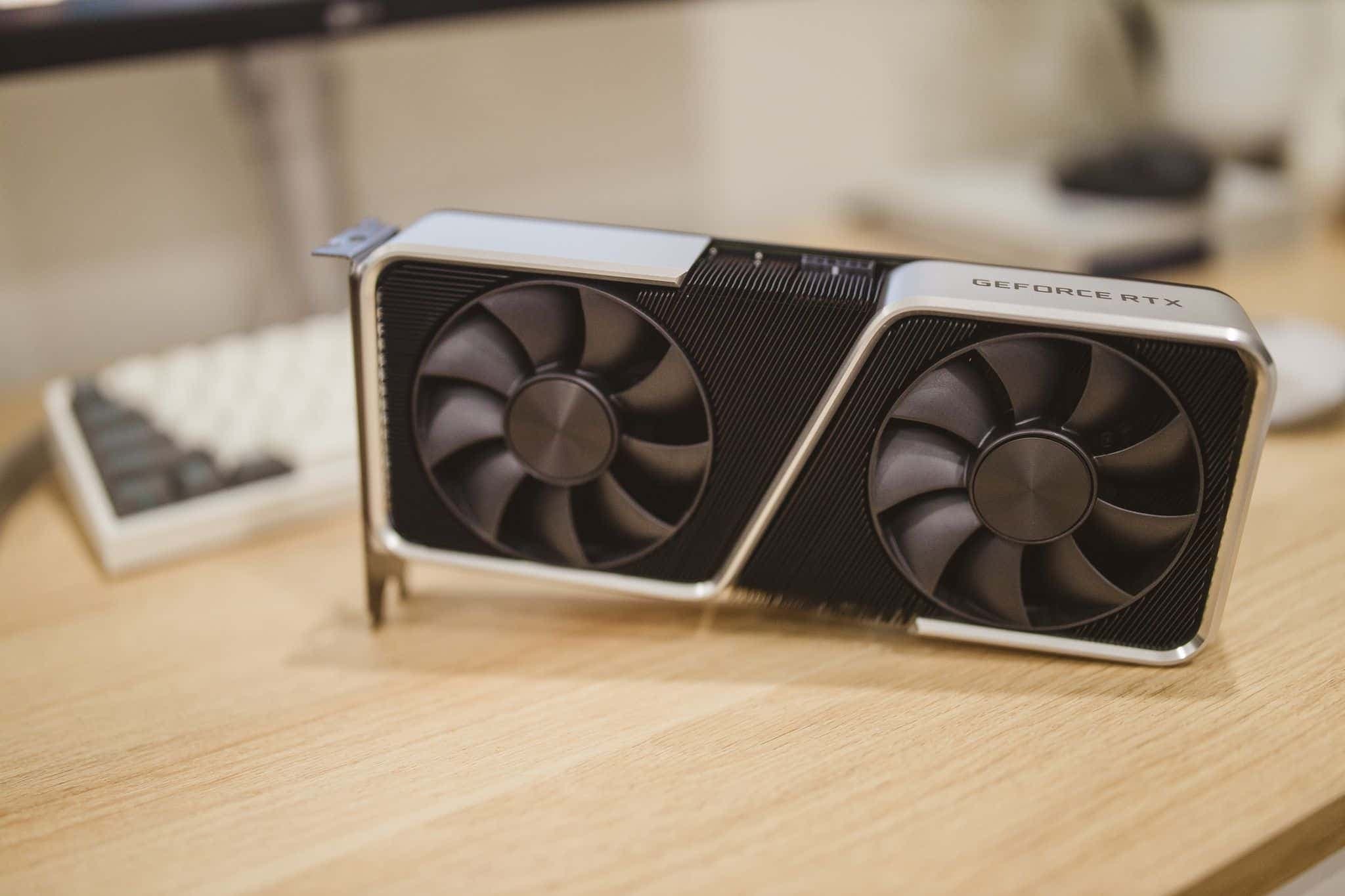 A GeForce RTX graphics card standing on a wooden desk.