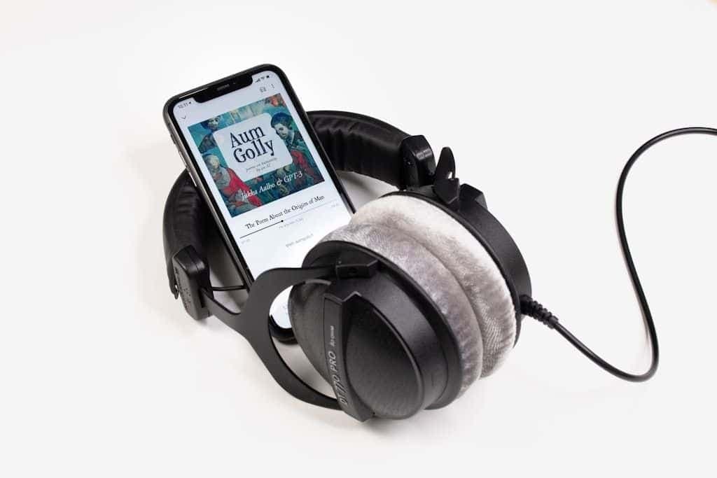 A phone playing an audiobook resting on a pair of studio headphones.