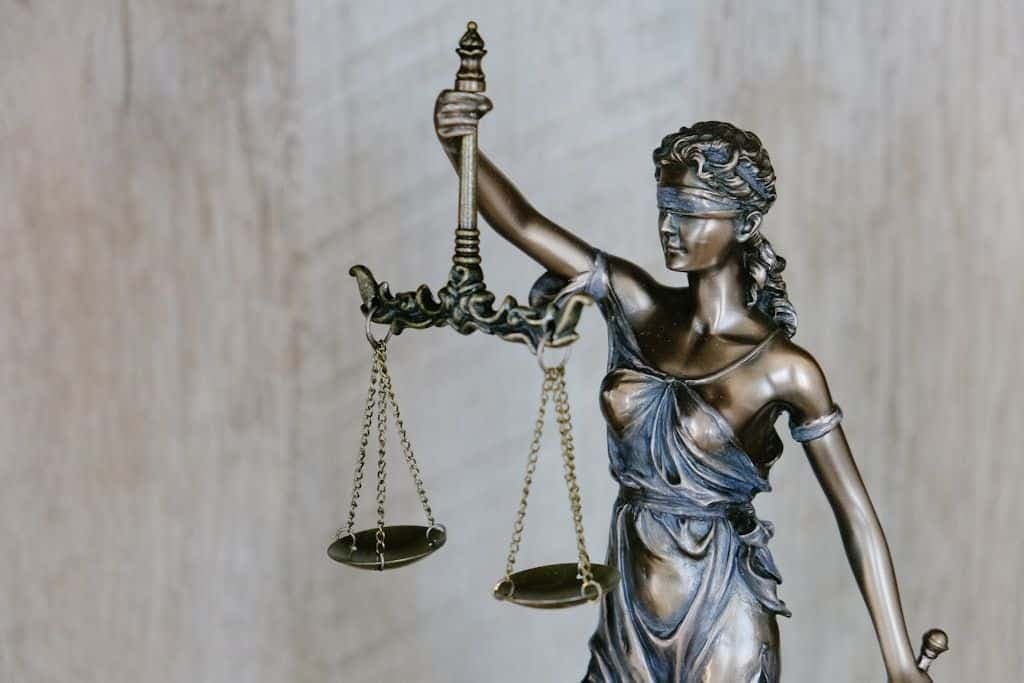 A bronze statue of Lady Justice holding scales, in soft daylight.