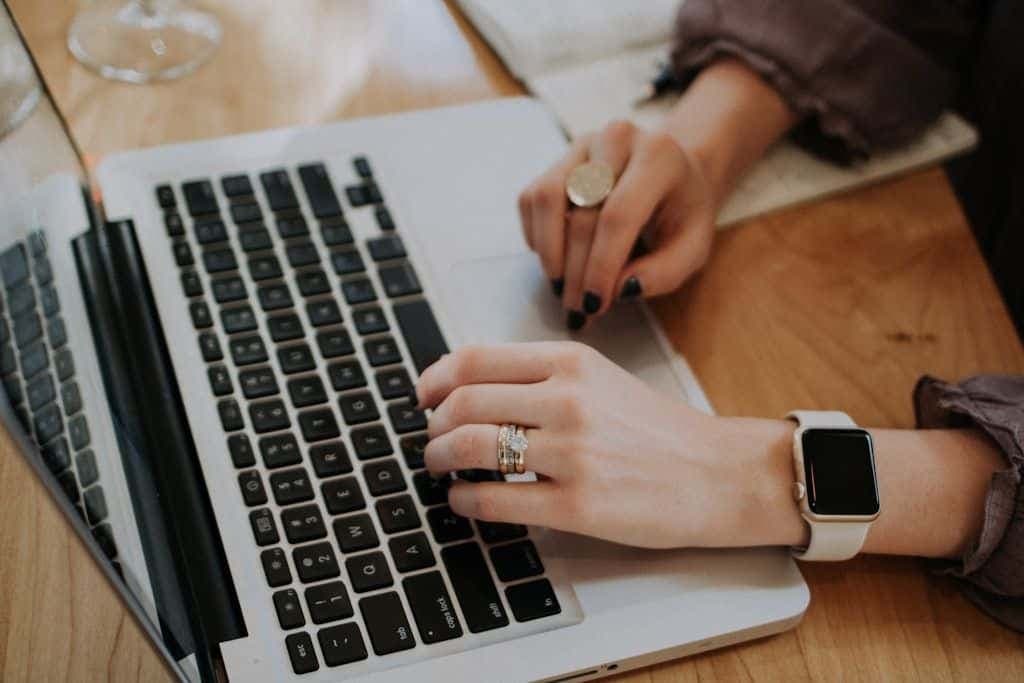 A person typing on a laptop at a bright desk.