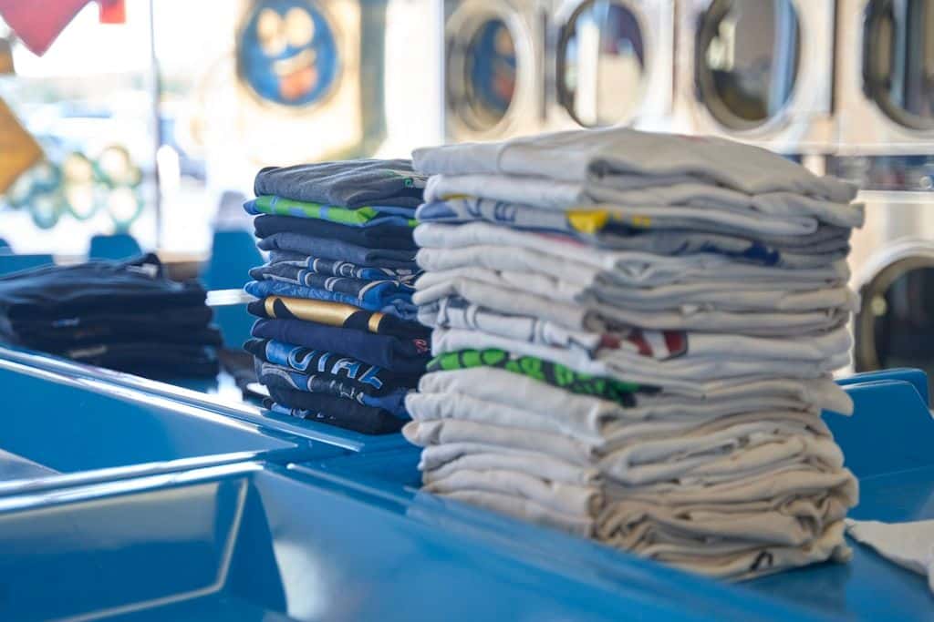 Stacks of folded shirts, close enough that the fabric folds, seams, and printed graphics read.