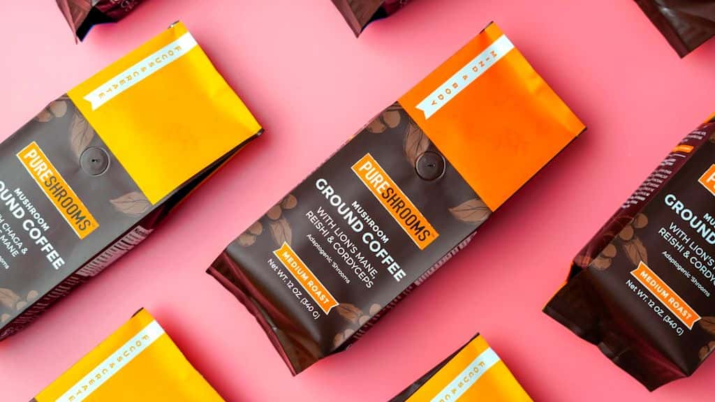 Coffee bags with a bold wordmark and small product type arranged on a pink background.