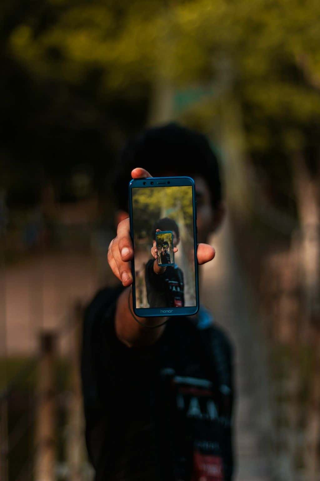 A person holding up a phone, filming vertical video.