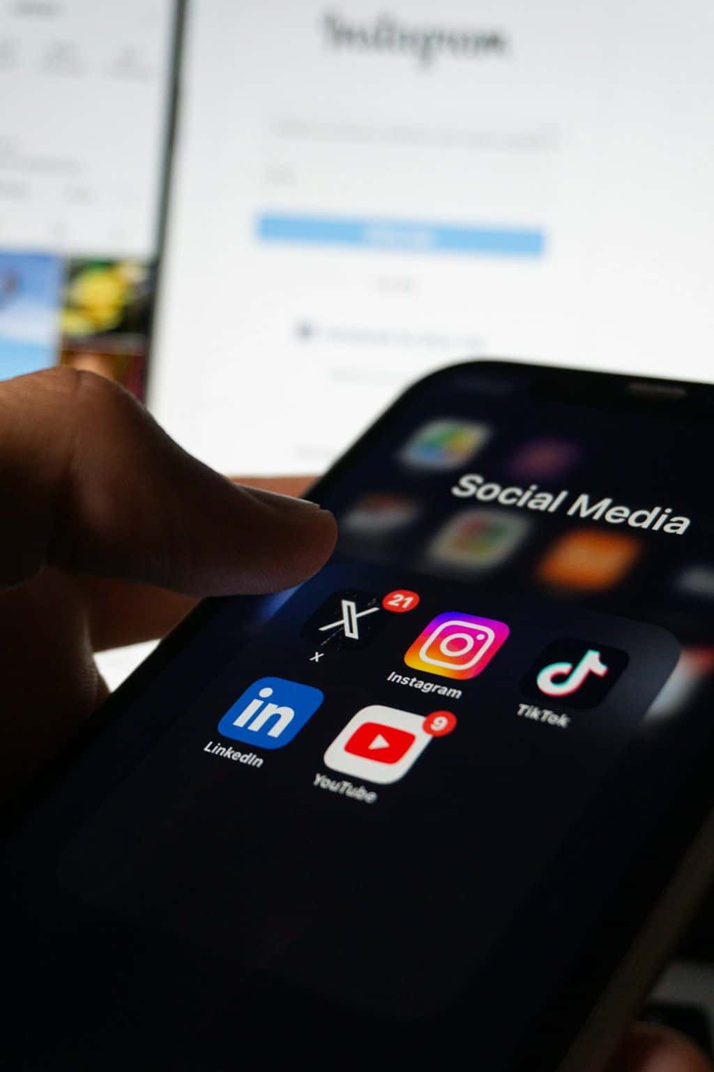 A hand holding a phone showing a social media feed.