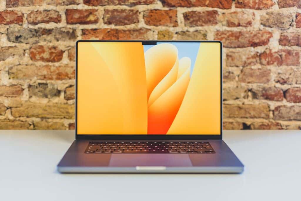 A MacBook Pro open on a clean wooden desk in a sunlit room.