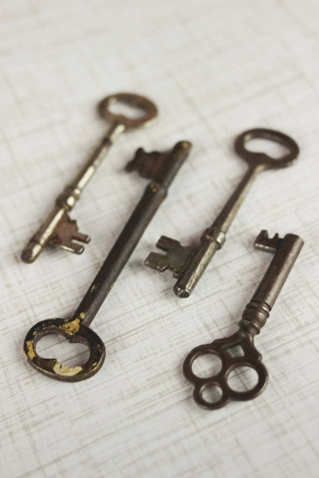 A set of four brass vintage skeleton keys laid out on a neutral background.