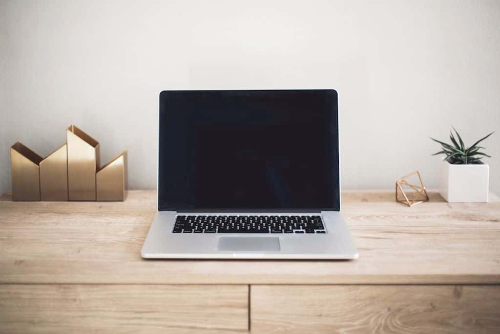 A MacBook on a wooden desk, open to a code editor.