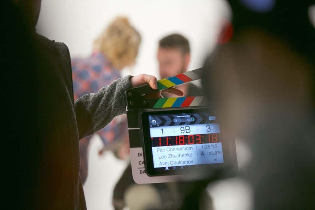A person holding a film clapperboard on a video production set.
