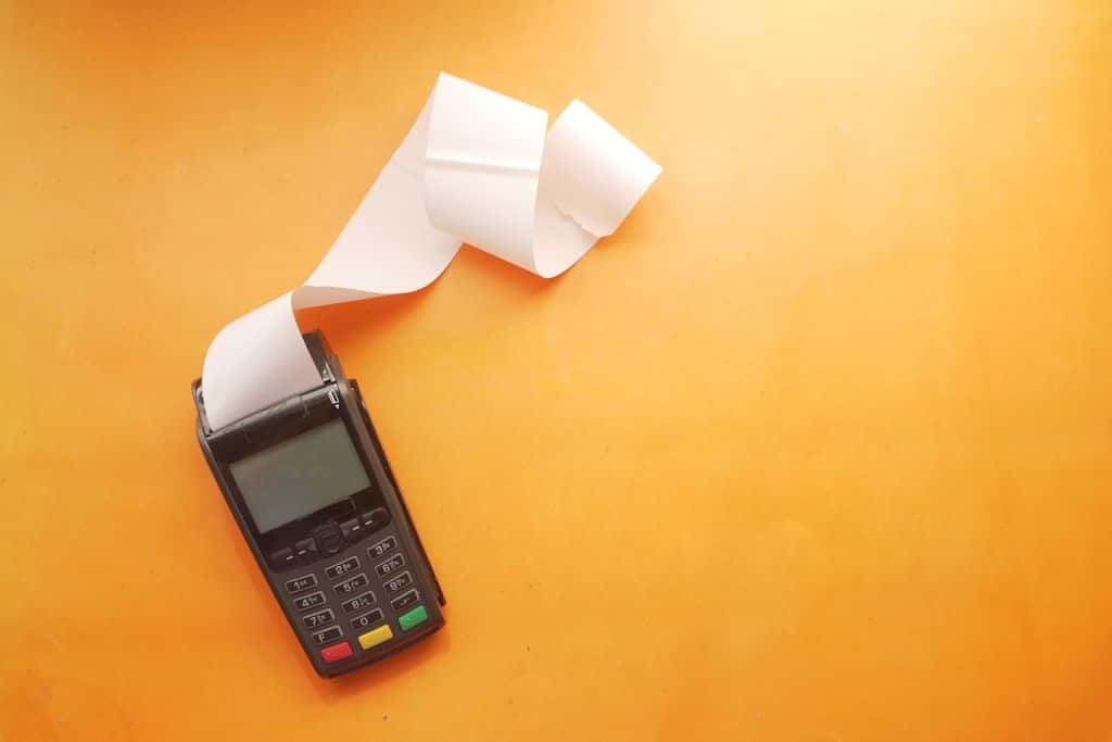 A long curl of paper receipt tape resting on a wooden table, photographed close up.