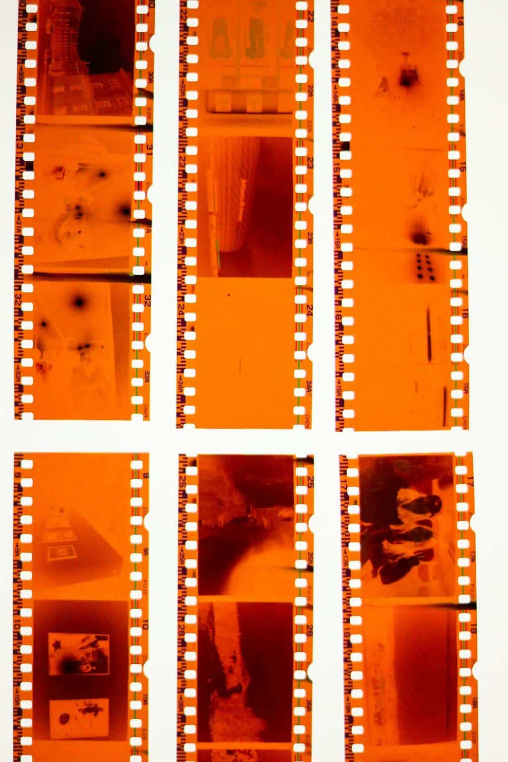 A set of six 35mm film strips arranged like a contact sheet on a flat surface, warm orange tones.