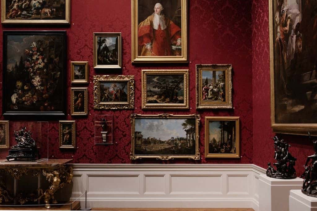 A salon-style wall of assorted framed pictures in different sizes, hung edge to edge.