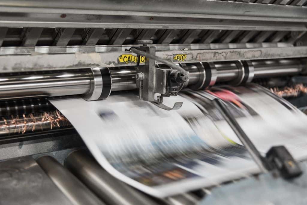 A rotary printing press at work, rolls of paper feeding through inked cylinders.