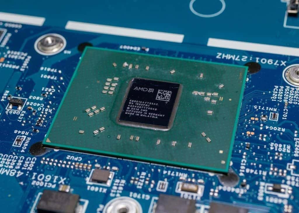 A close-up of a CPU chip seated on top of a motherboard, gold contacts catching the light.