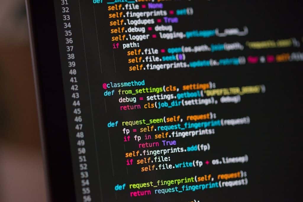 A monitor showing lines of code in a code editor on a developer's desk.