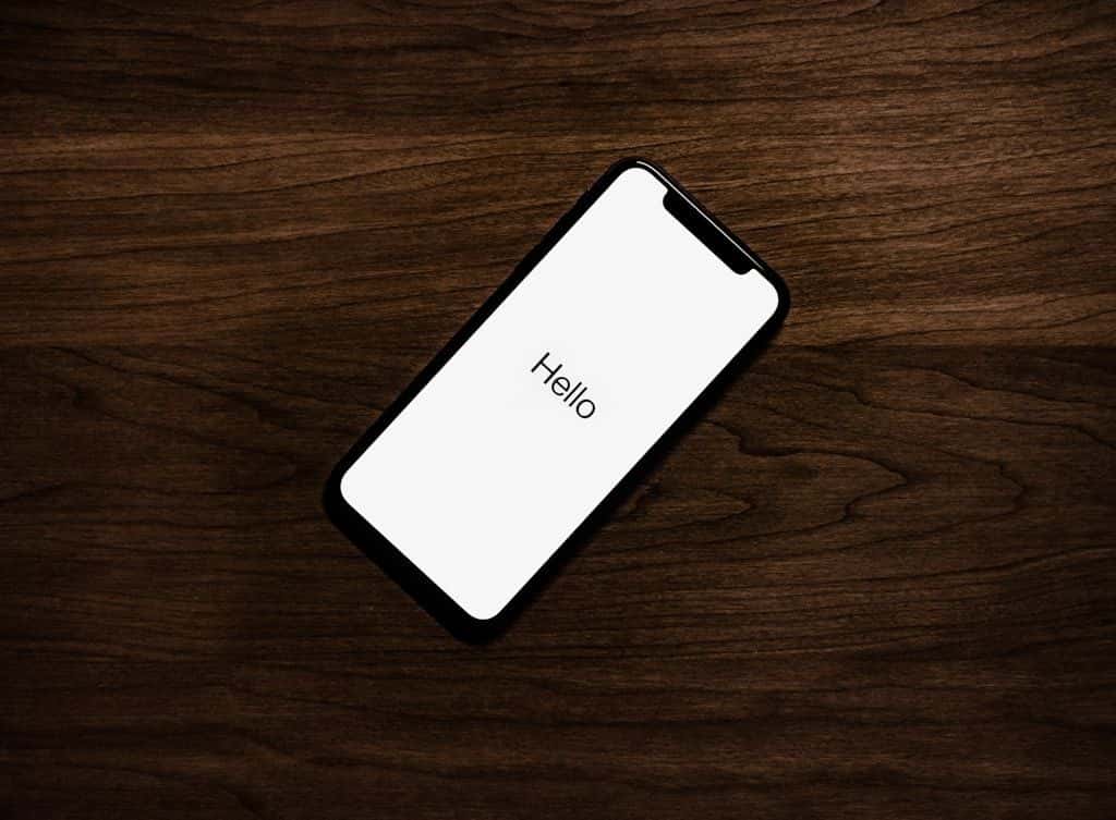 An iPhone resting face-up on a wooden desk surface.