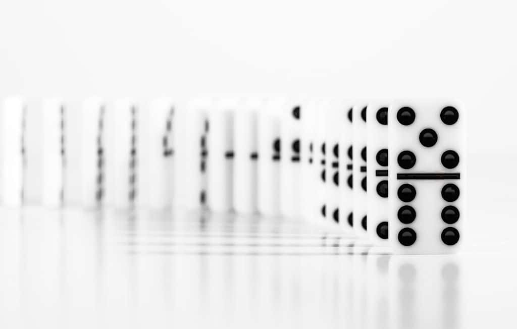 A row of dominoes standing in a line, ready to topple in sequence.