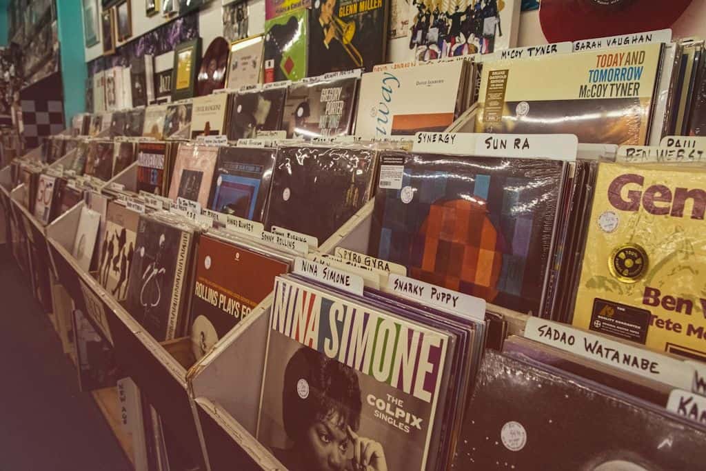 A wall of vinyl records arranged in tight rows in a small record shop, dense and selectively curated.