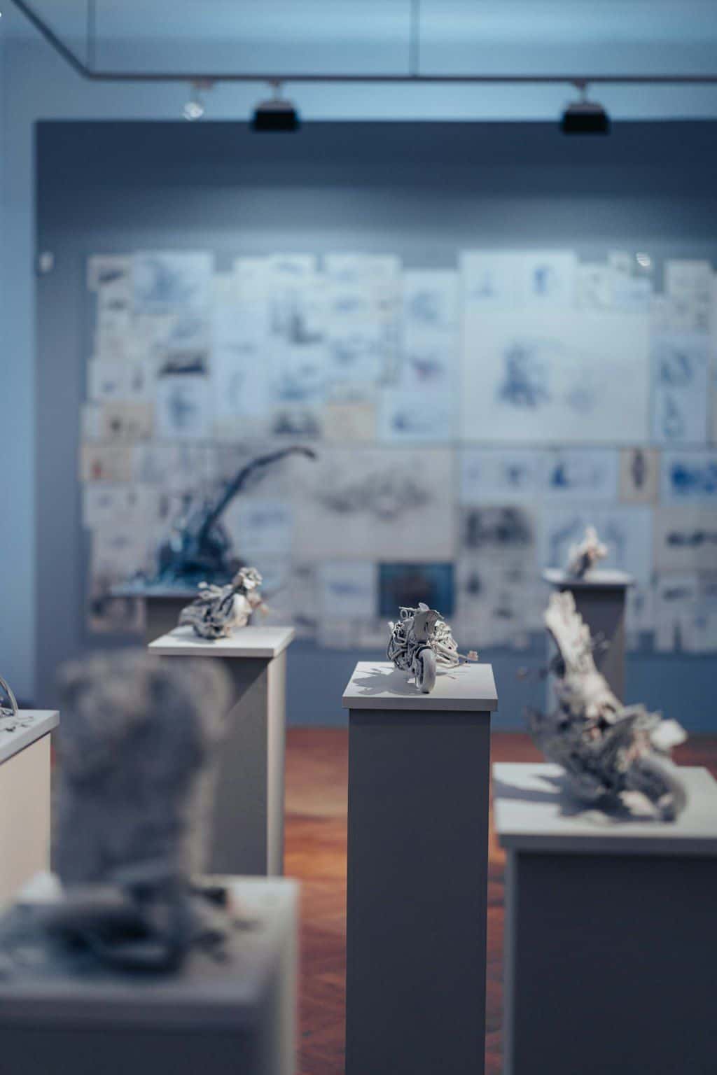 A spotlit museum vitrine holding three small artefacts on a clean white plinth.